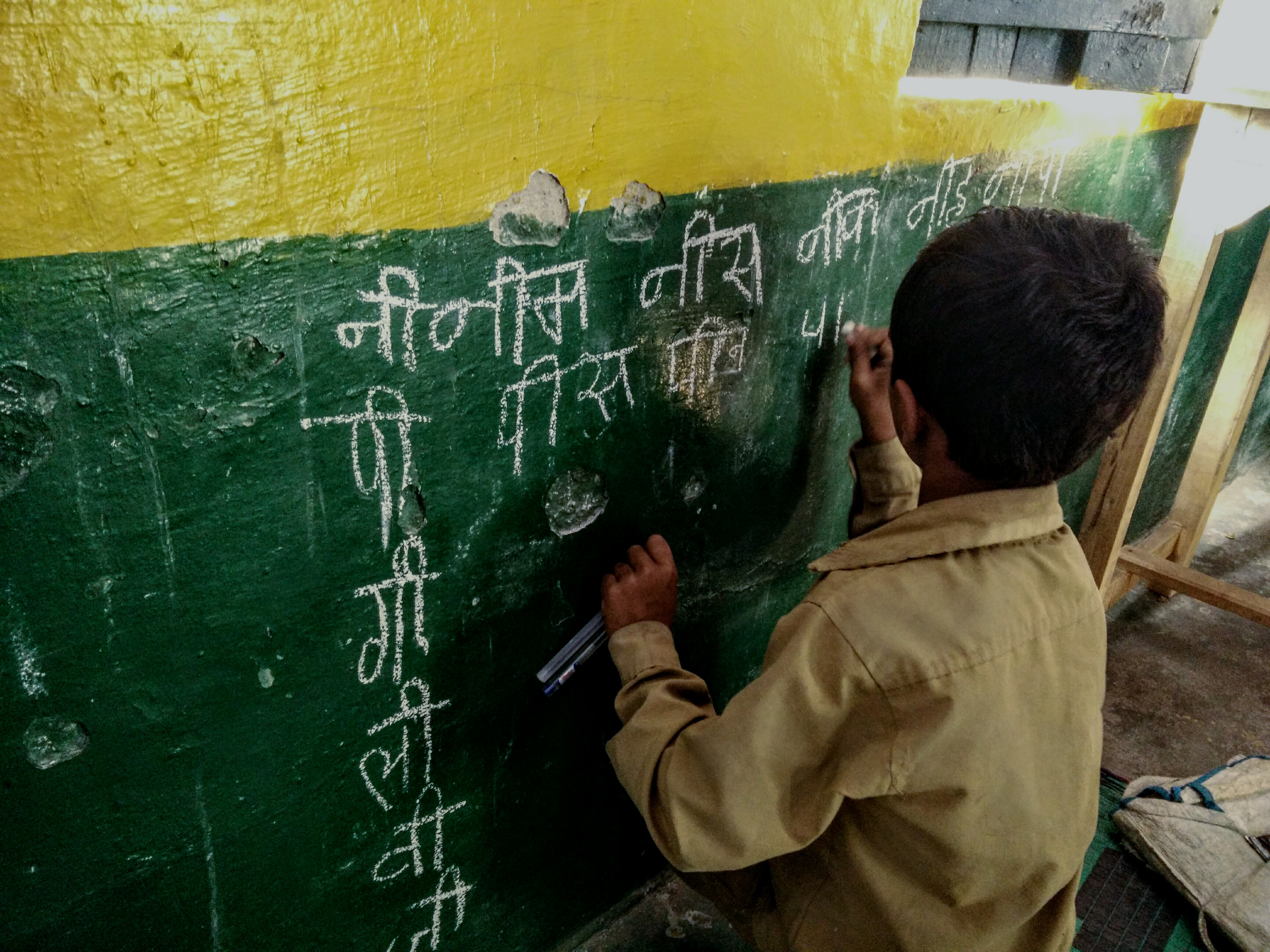 Reading activity in Karnataka A child uses chalk to write on the wall during a TaRL reading activity in Karnataka, India.